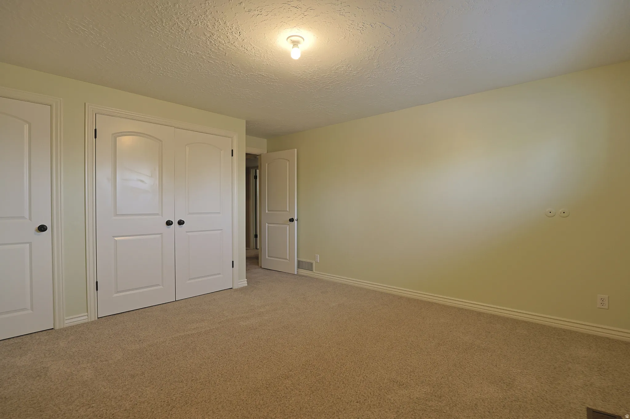 Unfurnished bedroom featuring a textured ceiling, carpet, and a closet