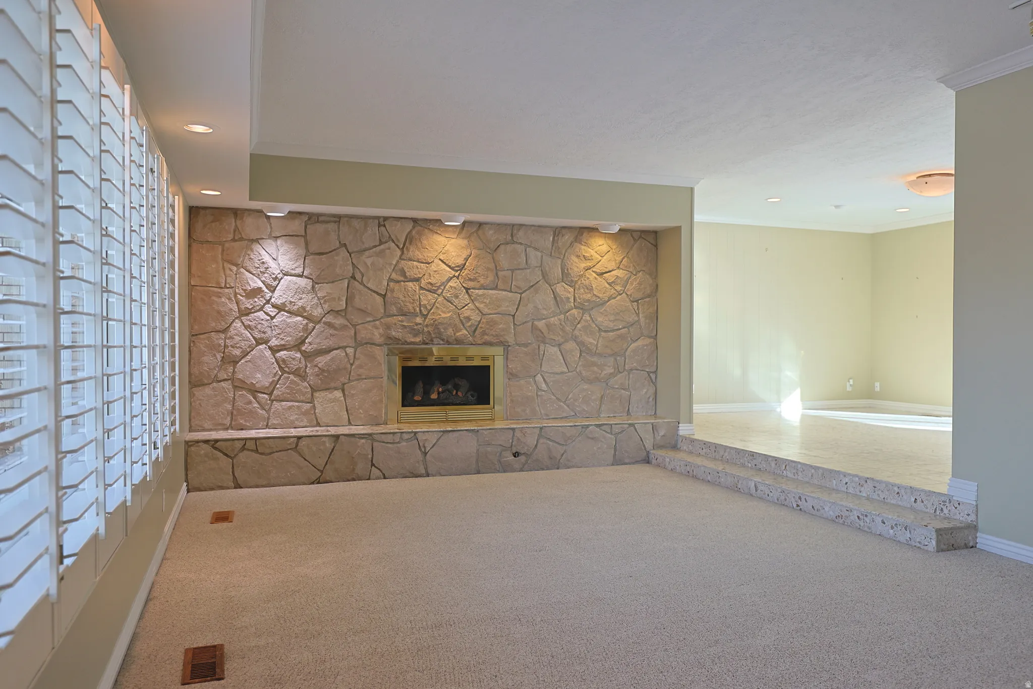 Unfurnished living room featuring a fireplace, carpet, crown molding, and recessed lighting