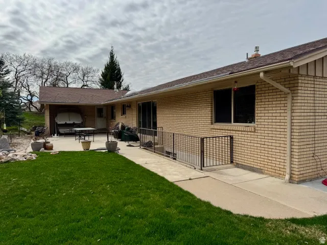 Rear view of house featuring a patio, brick siding, and a yard