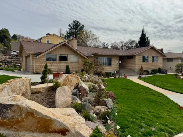 Single story home featuring brick siding, a front lawn, a garage, and a chimney