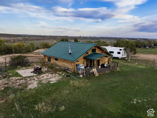 Log cabin exterior featuring a green metal roof, wooden siding, and an elevated porch