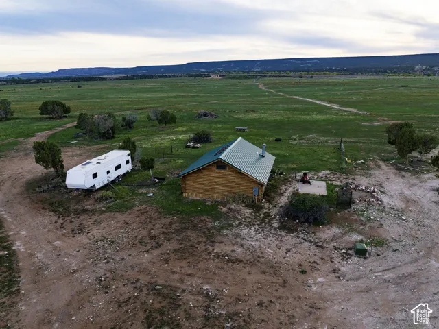 Log cabin construction with a metal roof, situated on a large, open parcel