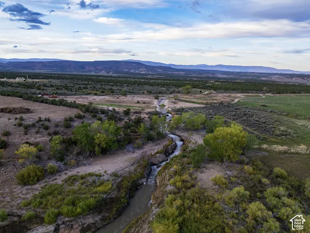 Winding river with surrounding natural vegetation, distant mountains, and partially visible developed land