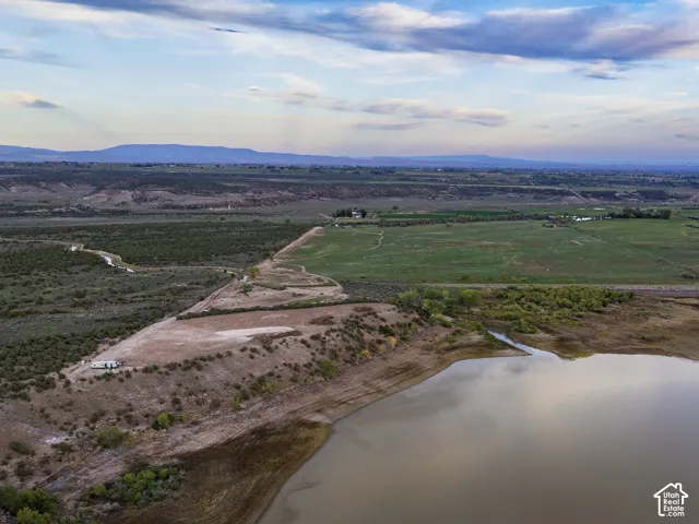 Expansive rural landscape featuring a large body of water, green fields, and distant mountain ranges