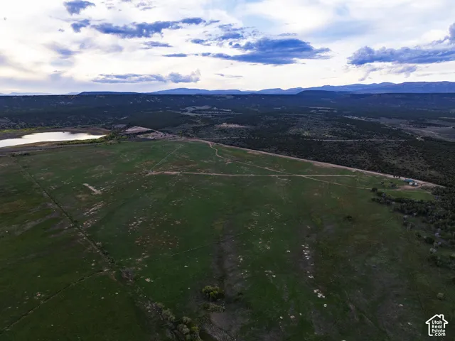 Expansive property featuring a large open field, distant water body, and mountainous background