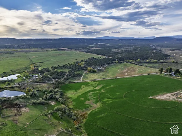 Expansive agricultural land featuring cultivated fields, natural water features, and distant mountain backdrops