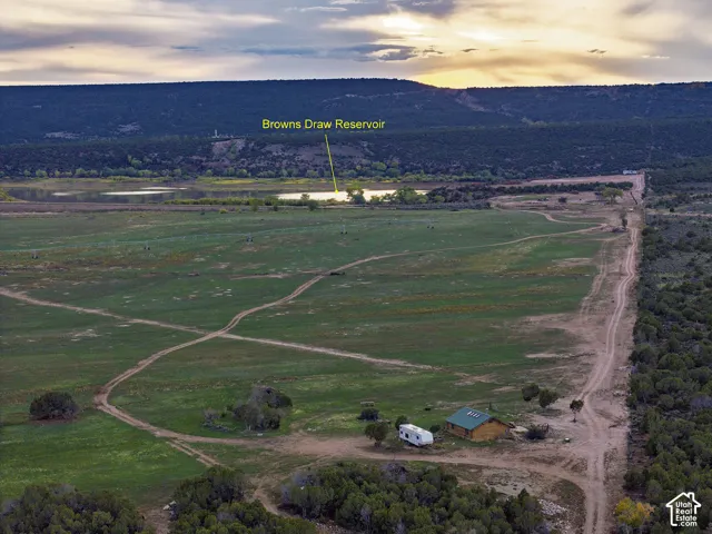 Expansive land featuring a reservoir, mountainous horizon, and a single-story structure with a green roof