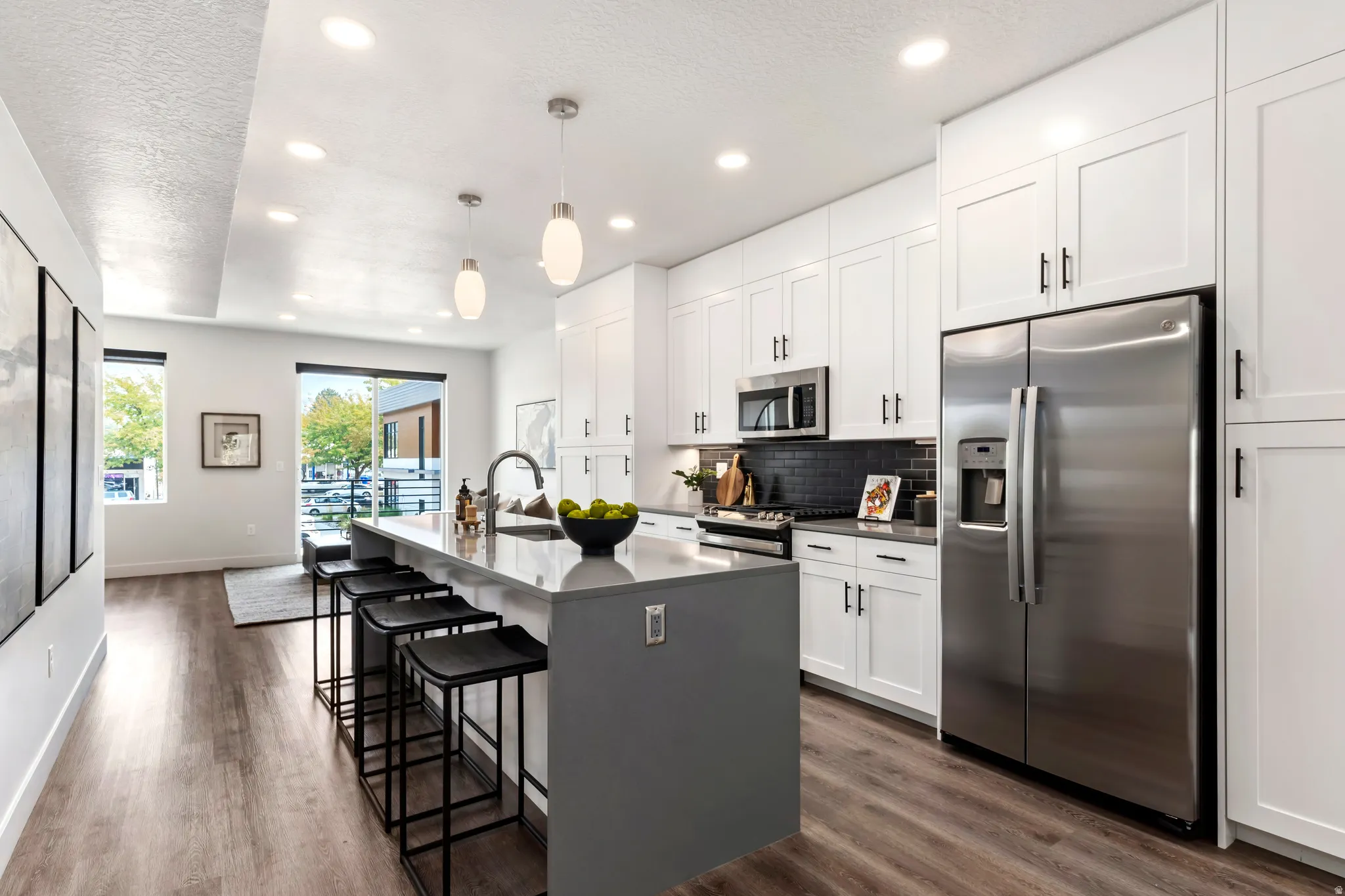 Kitchen featuring stainless steel appliances, white cabinetry, recessed lighting, a kitchen bar, and an island with sink. Model Home