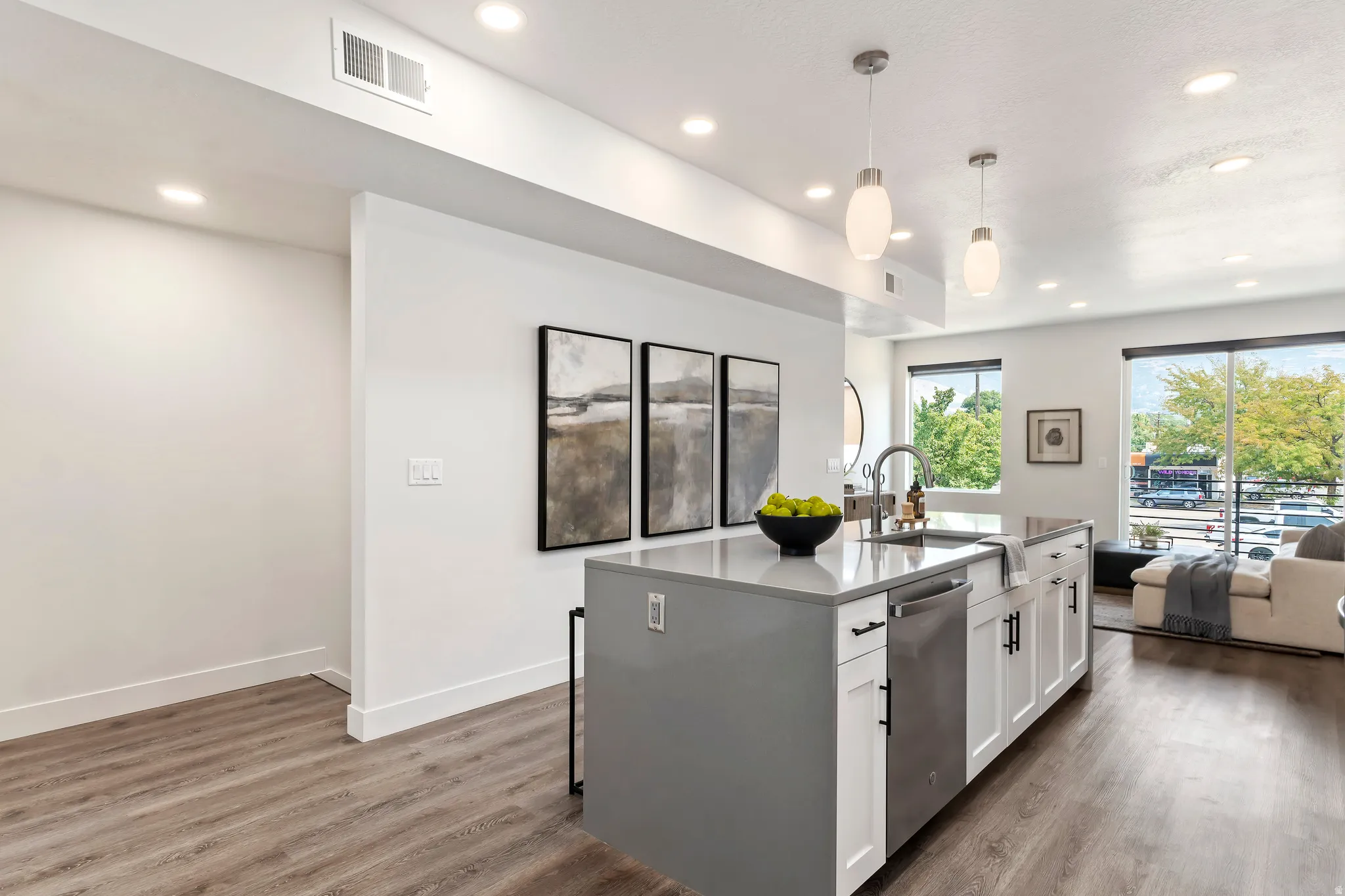 Kitchen featuring pendant lighting, dark wood-style floors, white cabinetry, open floor plan, and recessed lighting. Model Home
