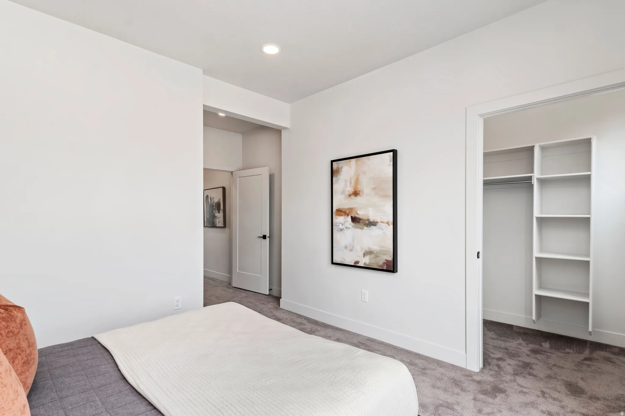 Carpeted bedroom with a walk in closet and baseboards. Model Home