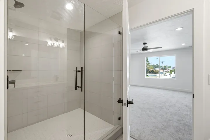 Glass-enclosed shower with white tiled walls and a hex-tile floor