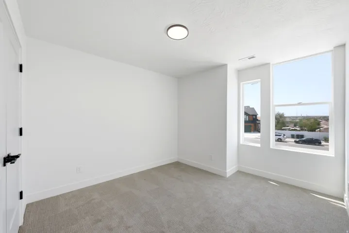 Bright interior with white walls, carpet flooring, a flush-mount ceiling light, and multiple windows
