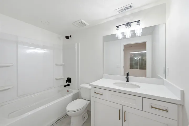 White vanity with modern gold-tone hardware, rectangular undermount sink, and a black-finish faucet