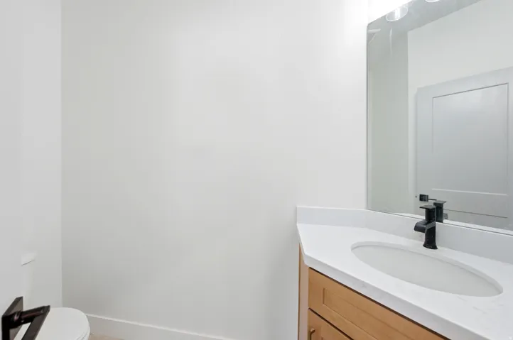 Built-in vanity with wood-finish cabinetry, integrated sink, white countertop, and matte black single-handle faucet