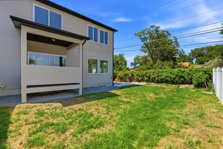 Rear exterior with covered patio, multiple windows, and a partially fenced yard