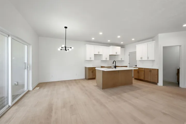 Open-concept living area featuring wood-finish flooring, a modern chandelier, and recessed lighting