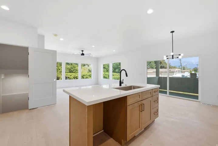Kitchen island with integrated sink, light-toned cabinetry, and solid surface countertop