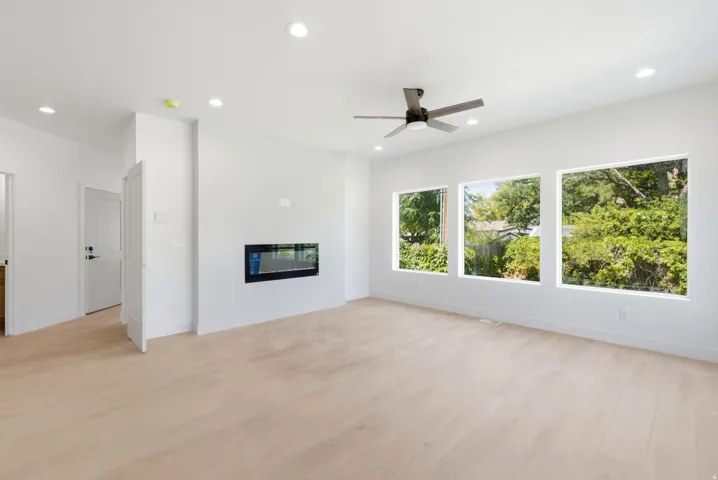 Expansive interior with light wood-finish flooring, recessed lighting, and a modern ceiling fan