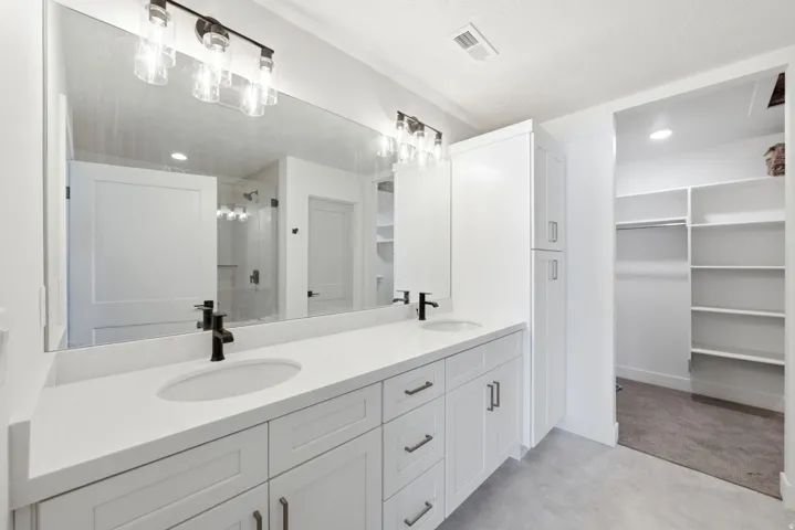 Double vanity with integrated sinks, white cabinetry, and matte black fixtures