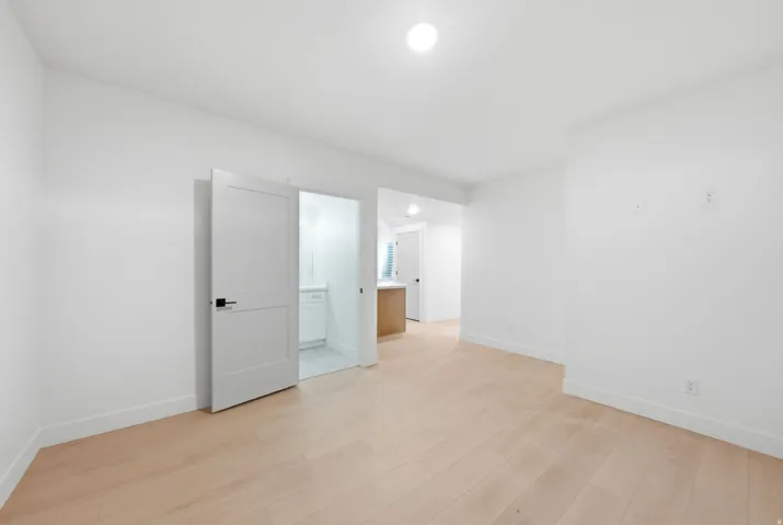 Light wood-finish flooring, recessed ceiling lighting, and crisp white walls