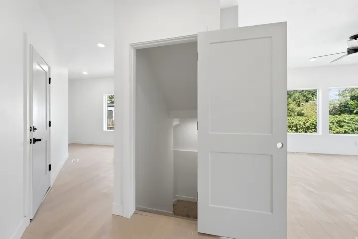 White interior doors with black hardware, recessed ceiling lighting, wood-finish flooring, built-in shelving, and multiple windows