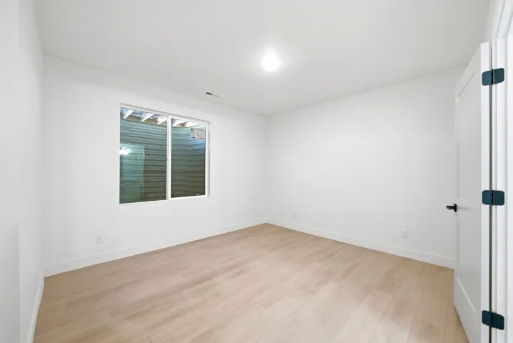 Recessed window with white trim, light wood-finish flooring, white walls, and a white door with black hardware