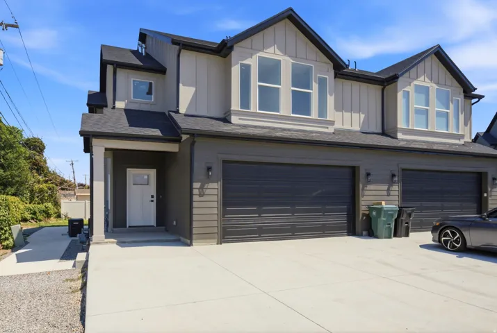 Contemporary exterior with vertical siding accents, multiple bay windows, a covered entry, and attached garages