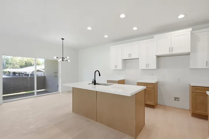 Kitchen featuring a center island, white cabinetry, recessed lighting, a contemporary chandelier, and wood-finish flooring
