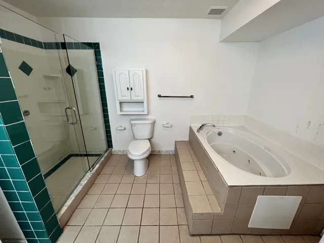 Full bathroom featuring a stall shower, light tile patterned flooring, and a jetted tub