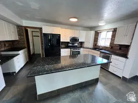 Kitchen featuring stainless steel appliances, a center island, white cabinetry, and a textured ceiling
