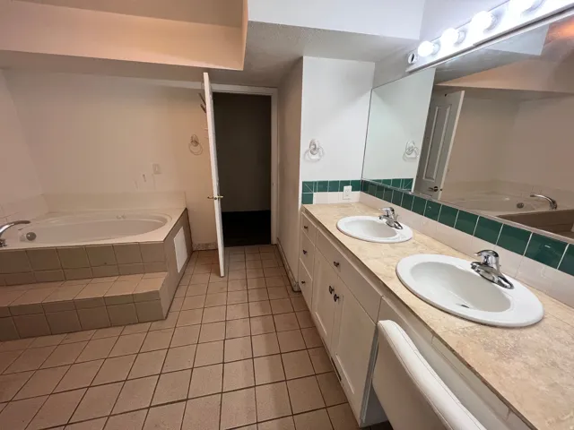 Bathroom featuring a bath, double vanity, and light tile patterned flooring