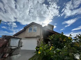 View of front of house with driveway and stone siding