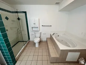 Full bathroom featuring a shower stall, light tile patterned flooring, and a jetted tub