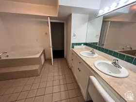Bathroom featuring a garden tub, double vanity, and light tile patterned floors