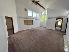 Unfurnished living room featuring beam ceiling, carpet, high vaulted ceiling, and a ceiling fan