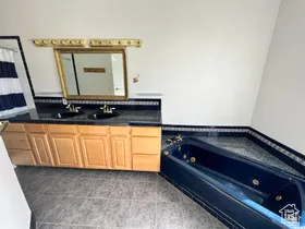 Bathroom featuring a tub with jets, double vanity, and light tile patterned floors