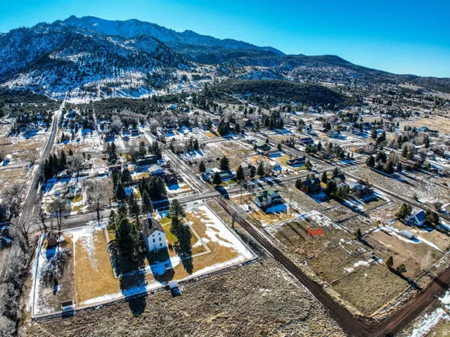 Aerial view of property and surrounding area featuring a mountain backdrop and nearby suburban area