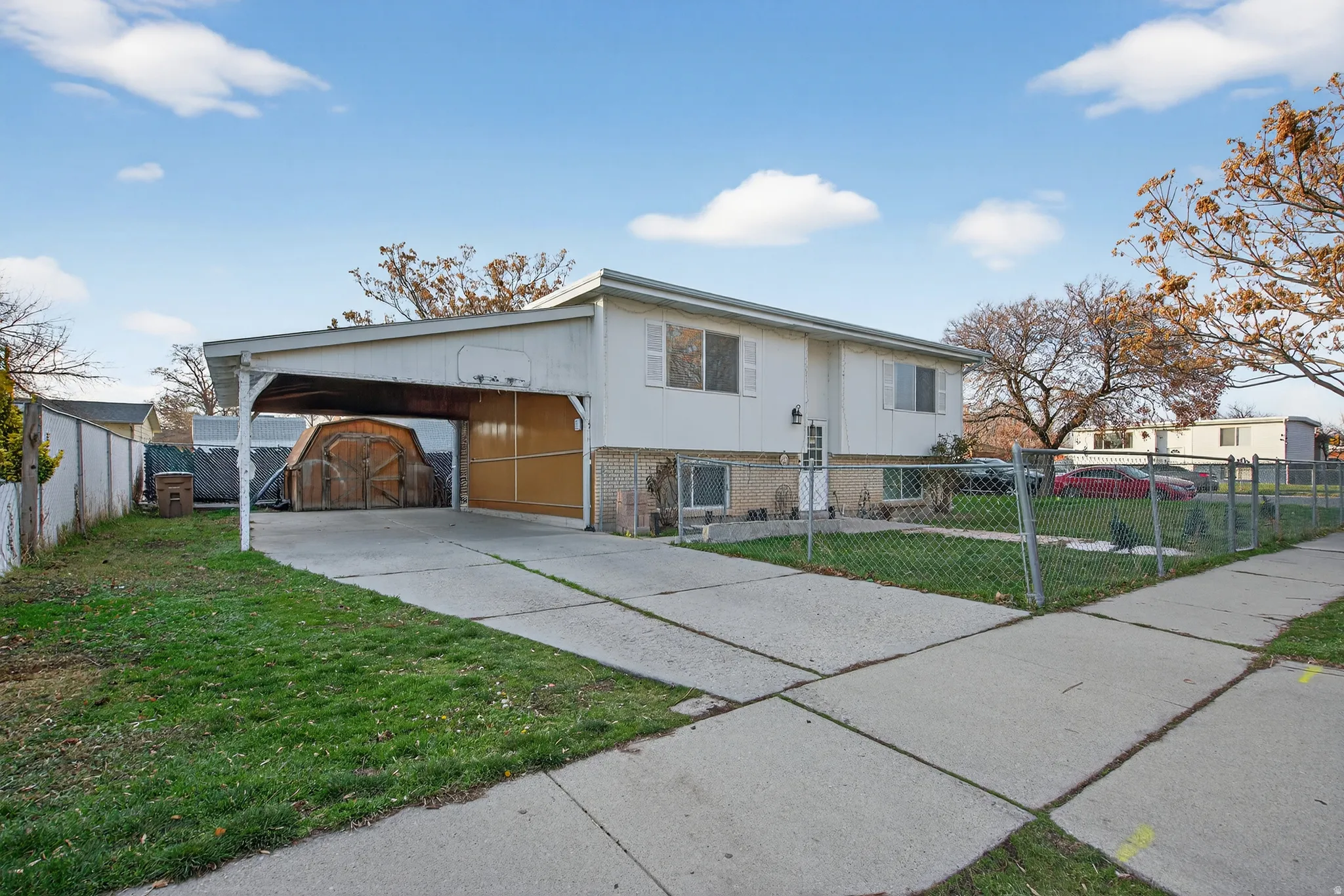 View of front of home featuring brick siding, driveway, a fenced front yard, and a carport