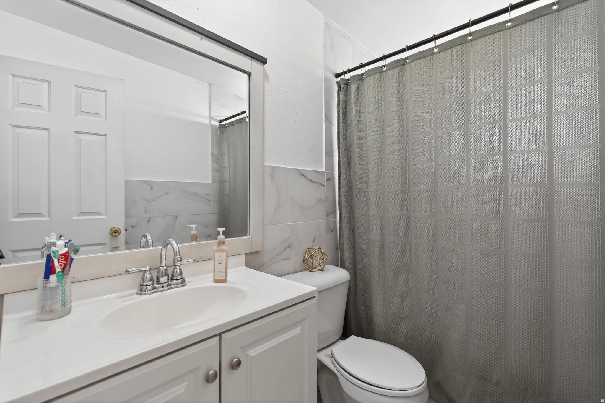 Bathroom with tile walls, vanity, a shower with shower curtain, and a wainscoted wall