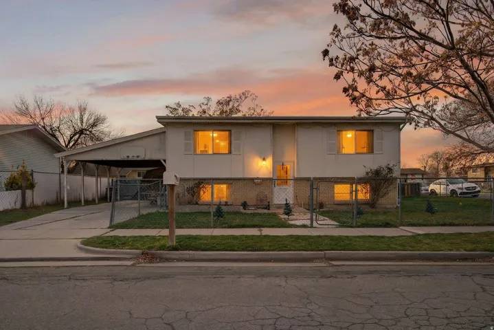 Split foyer home with driveway, a fenced front yard, brick siding, and a gate