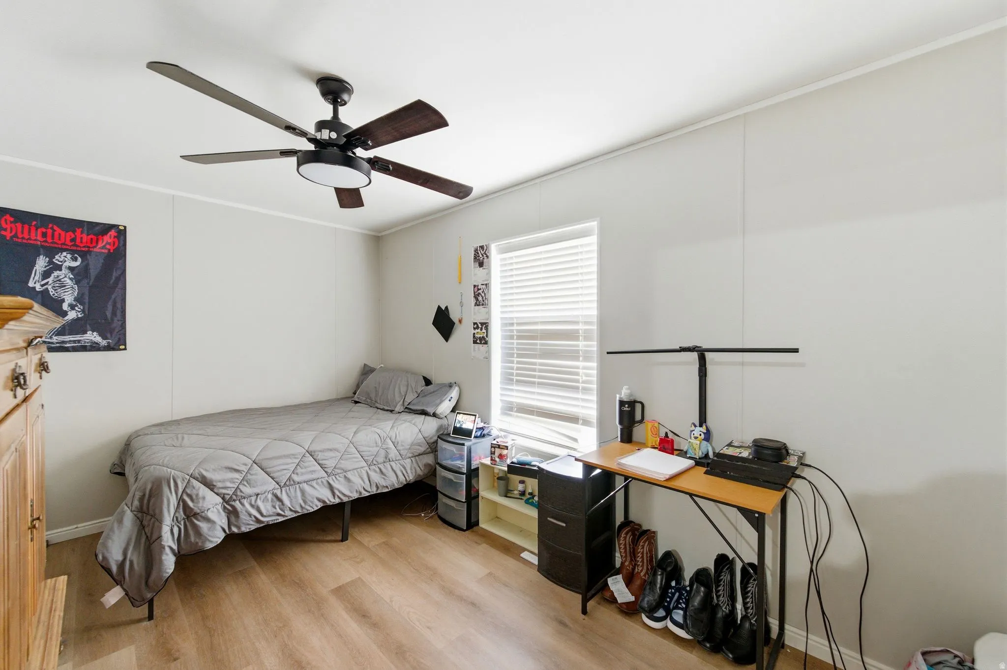 Bedroom with ceiling fan, light wood-style flooring, crown molding, and a decorative wall
