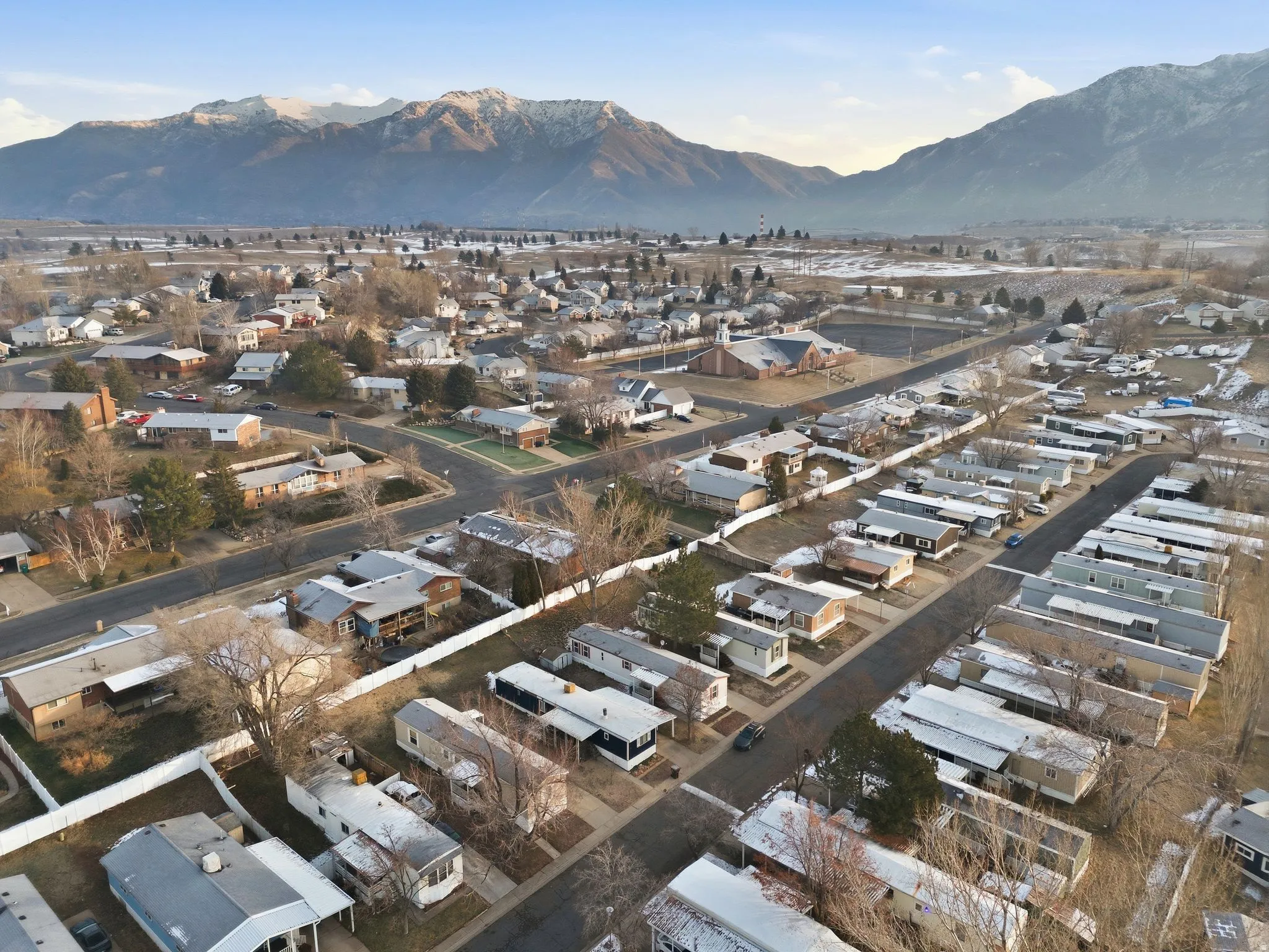 Aerial view of property and surrounding area featuring nearby suburban area and a mountainous background
