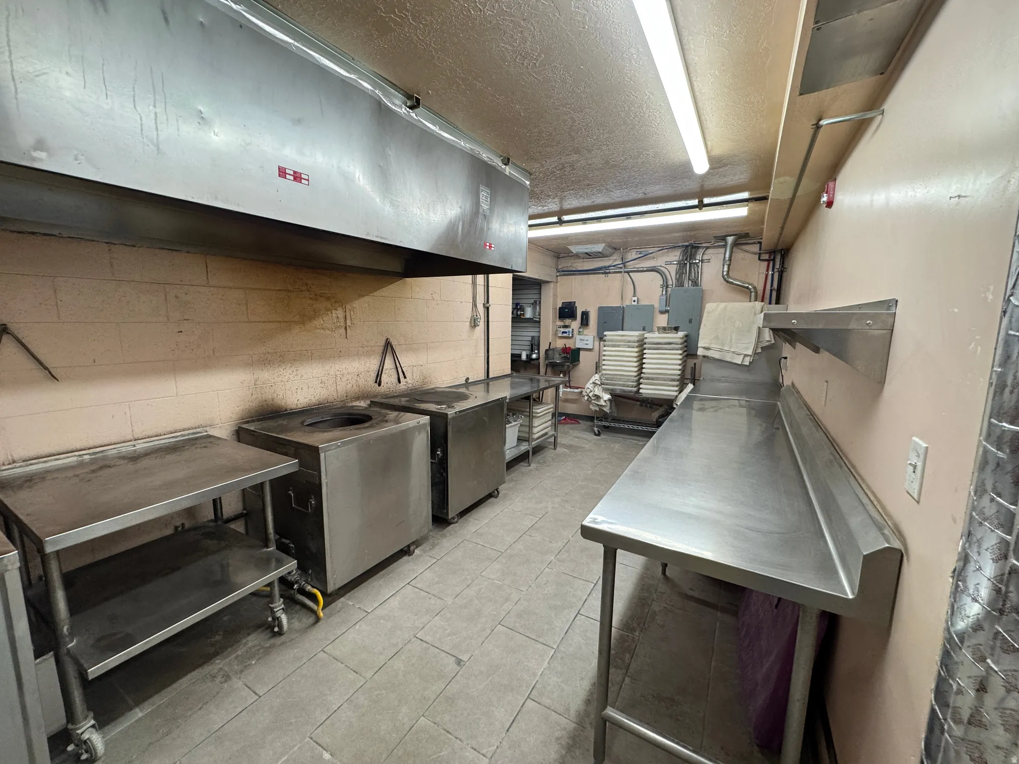 Kitchen with stainless steel countertops, a textured ceiling, stainless steel refrigerator, and electric panel