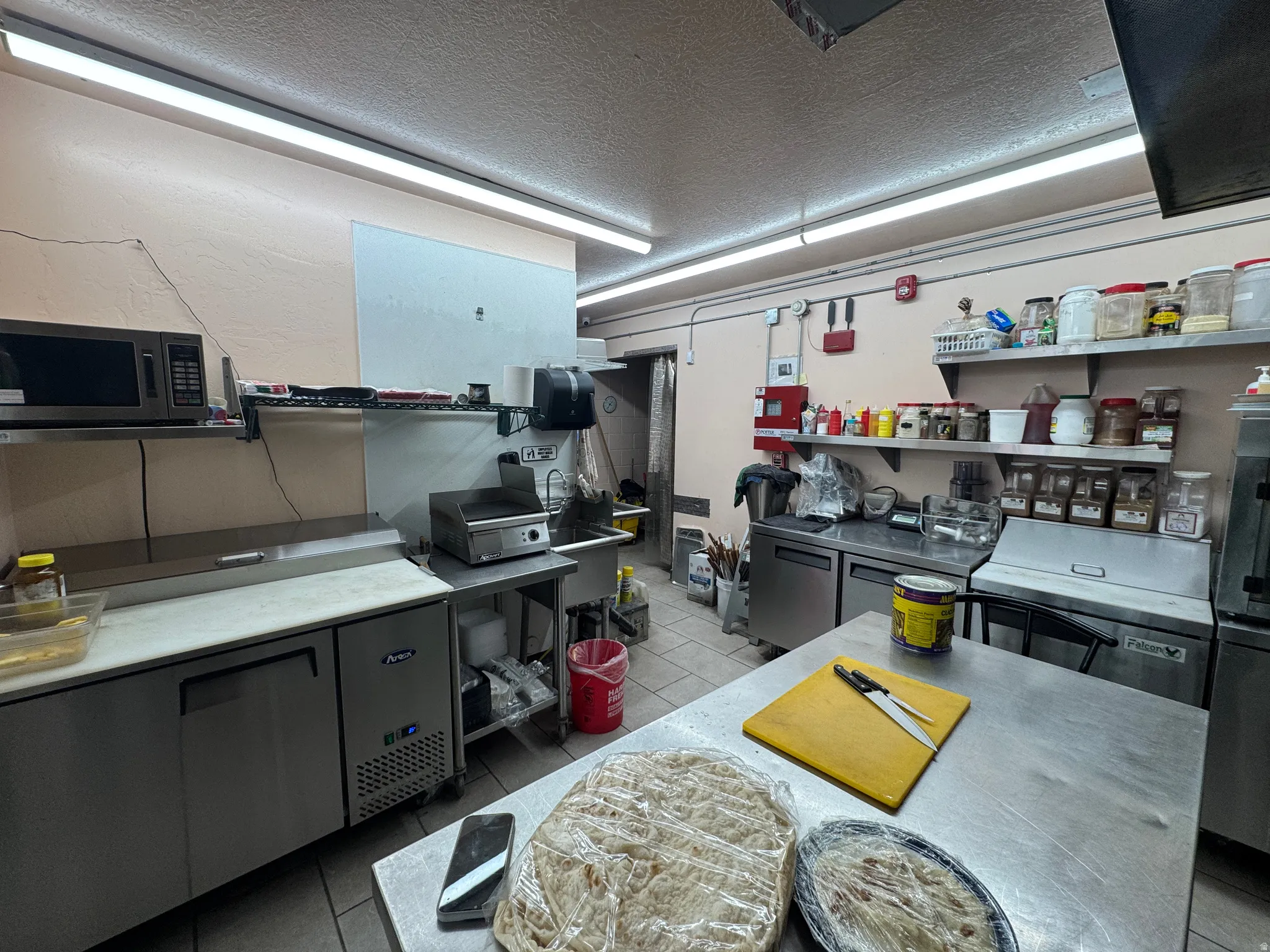 Kitchen featuring a textured ceiling, stainless steel microwave, and light countertops