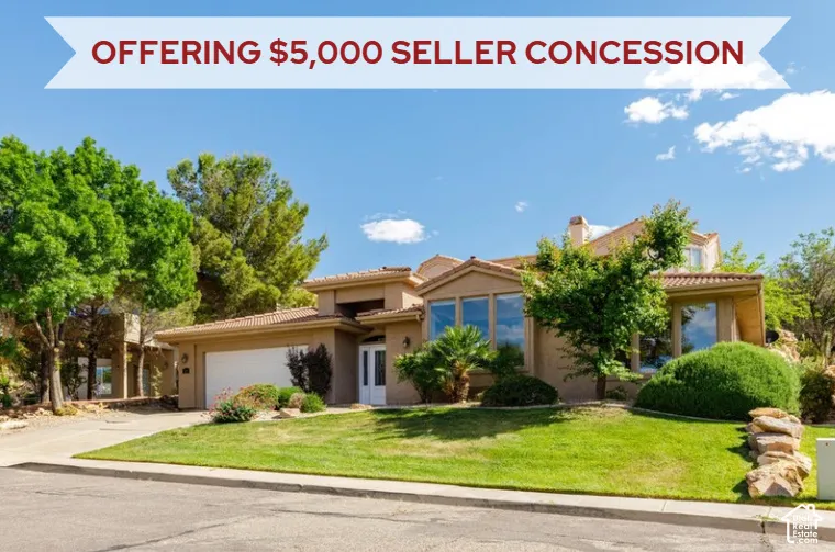 Stucco exterior residence featuring an attached two-car garage, mature trees, and a landscaped lawn