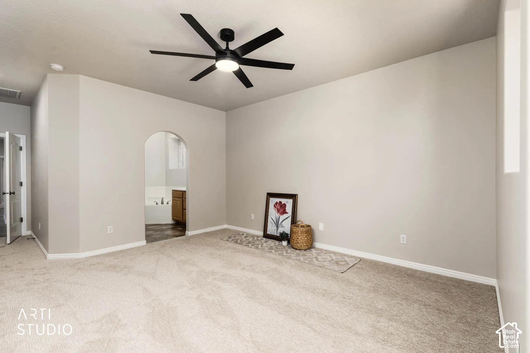 Unfurnished bedroom with ensuite bath, carpet, ceiling fan, and arched walkways