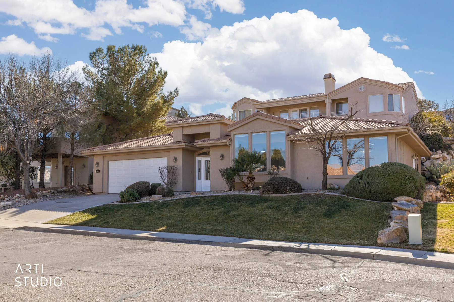 Mediterranean / spanish home featuring a front lawn, driveway, stucco siding, a tile roof, and an attached garage