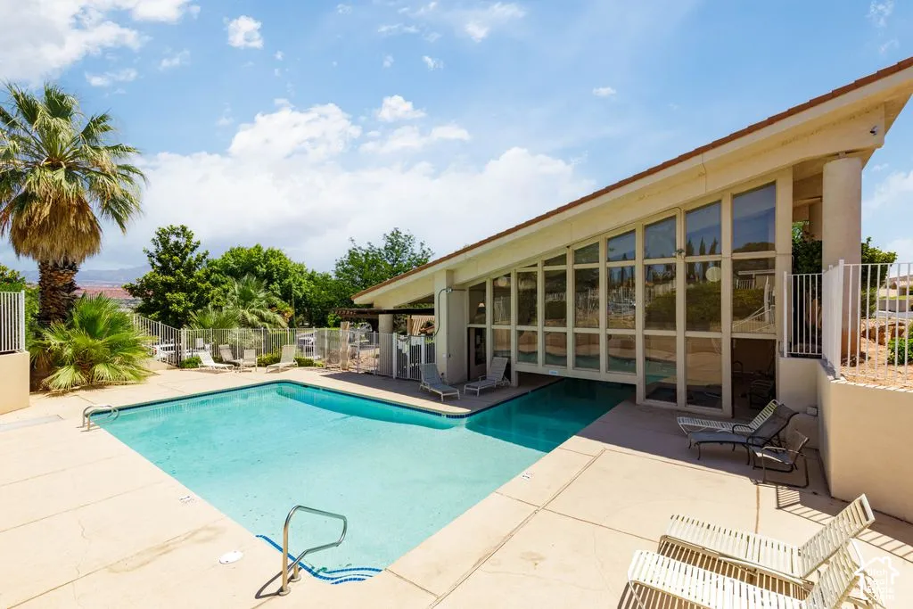 Outdoor swimming pool with concrete decking, surrounded by mature palm trees and lush landscaping