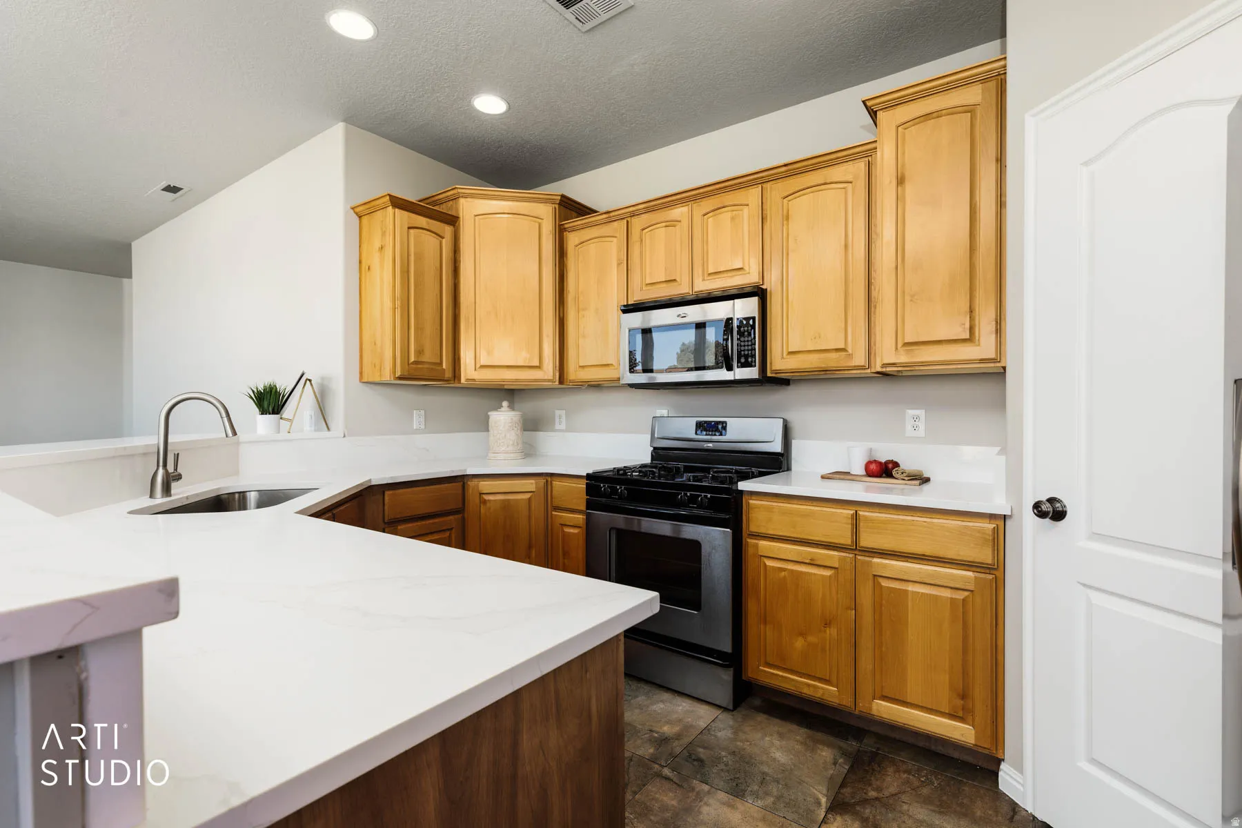 Kitchen with stainless steel appliances, a textured ceiling, light stone countertops, and recessed lighting