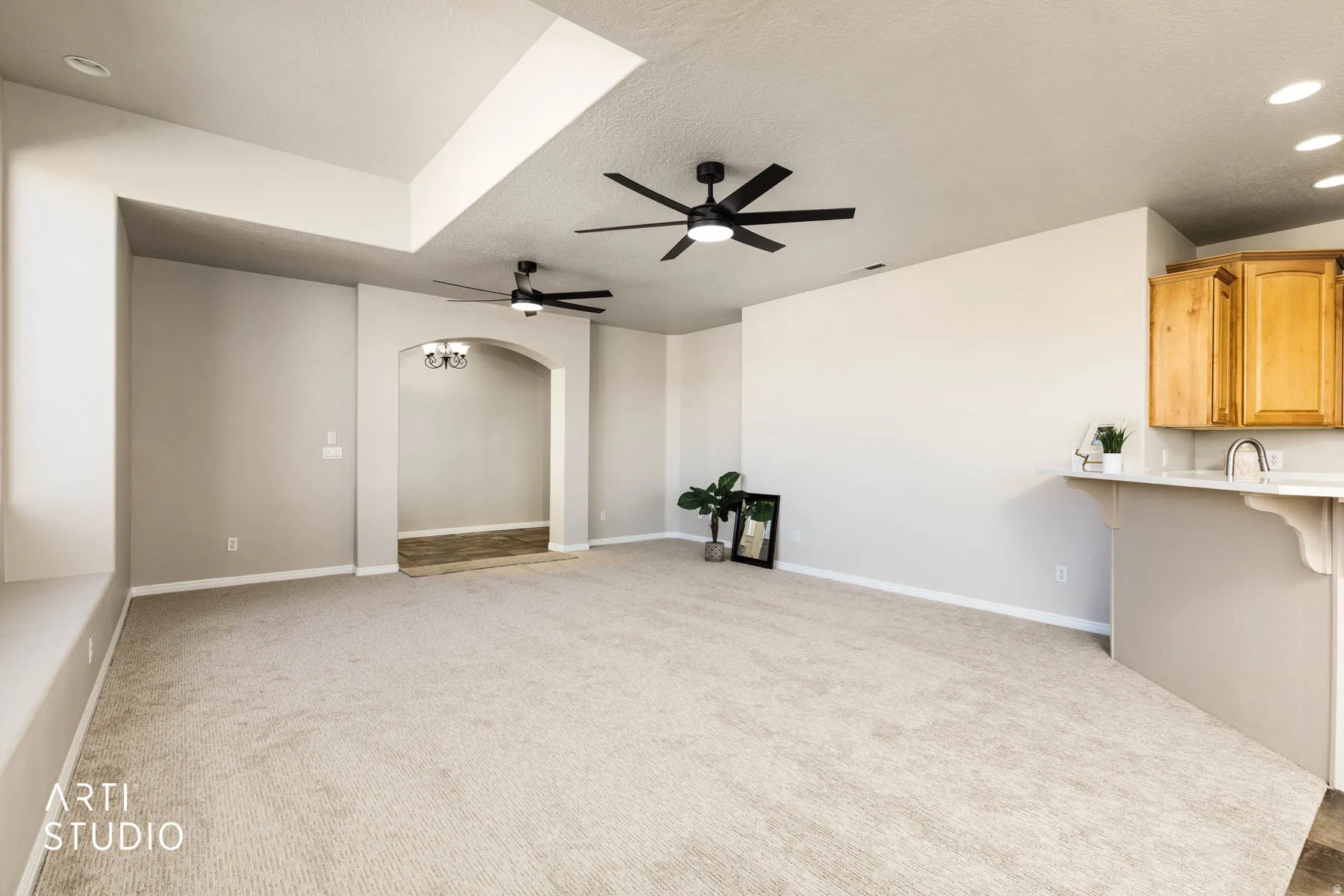 Unfurnished living room with light colored carpet, arched walkways, recessed lighting, a textured ceiling, and ceiling fan
